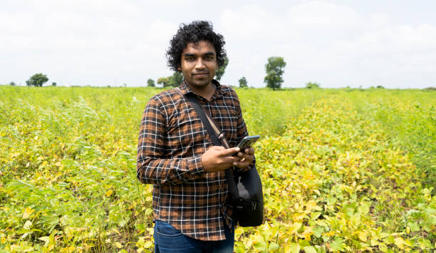 Indian farmer using smart phone at green agriculture field.